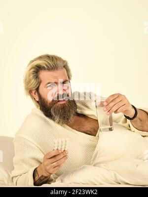Überschläfring kann Körper in Gefahr für metabolische Probleme setzen. Kater Konzept. Mann schmerzhafte Leidenden Gesicht Aufwachen am Morgen. Hipster trinken Wasser Nehmen Sie Medikamente. Kopfschmerzkater. Abhilfe durch Kater. Stockfoto