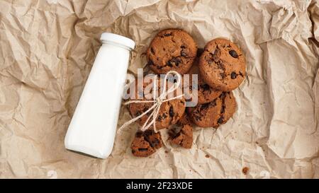 Kekse mit Schokoladentropfen auf Bastelpapier und eine Flasche Milch Stockfoto