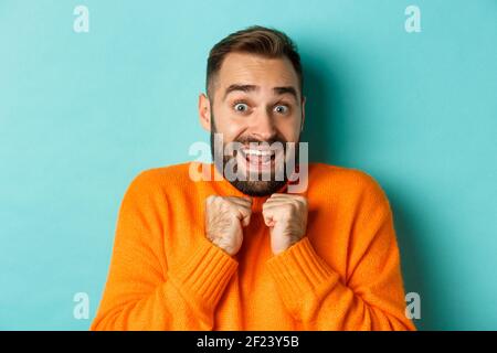 Nahaufnahme eines erschrocknen Mannes, der keuchte und die Hände auf die Brust drückte, schockiert auf die Kamera starrte und auf hellblauem Hintergrund stand Stockfoto