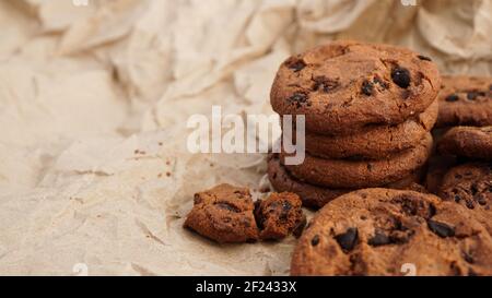 FlatAnsicht von handgefertigten Schokoladenkeksen mit Schokoladenstückchen auf dem Backen Papier Stockfoto