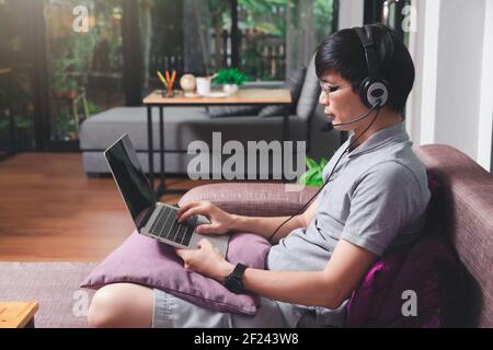 Businessman Meeting online per Videoanruf auf Laptop im Heimbüro. Mann tragen Kopfhörer Videoanrufe oder Fernunterricht e-leaning Online-Kurs. Stockfoto