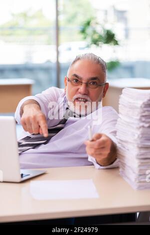 Gealterter Geschäftsmann, unzufrieden mit übermäßiger Arbeit Stockfoto