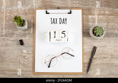 Schreiben Tax Day mit Holzwürfel April 15th Blatt Papier, Gläser, Stift auf Desktop. Flach liegend. Draufsicht. US-Frist zur Zahlung von Steuern. Stockfoto