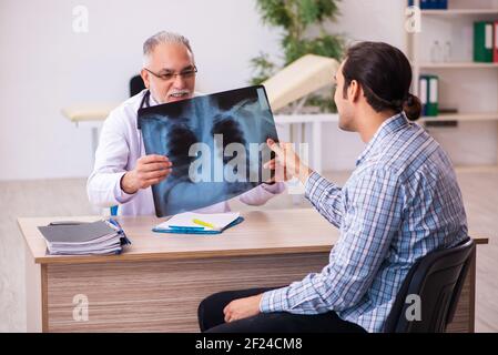 Junger männlicher Patient besucht alten männlichen Arzt Stockfoto