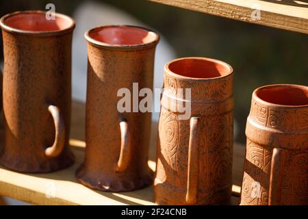 Tonbecher stehen in Reihen auf einem Holzregal. Stockfoto