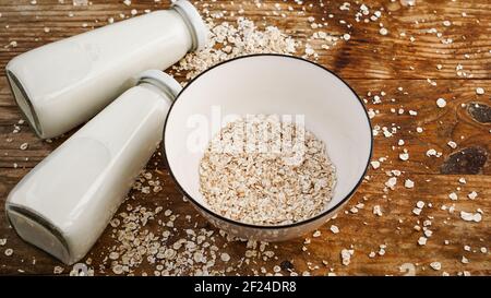 Haferflocken in einer weißen Schüssel und Flaschen mit frischer Milch Stockfoto