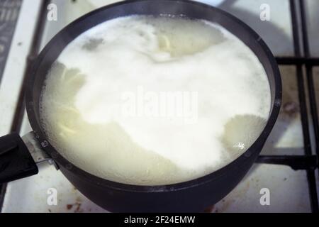 Kochendes Wasser mit Nudeln in kleinen schwarzen Kochtöpfen mit Antihaftbeschichtung. Kochen auf gebeizten Gasherd Stockfoto