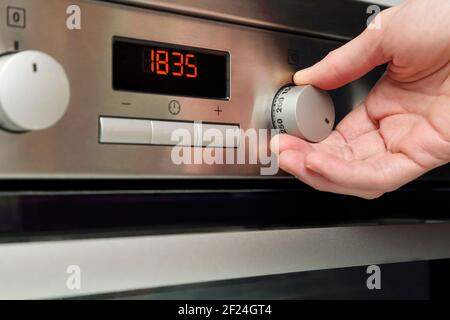 Nahaufnahme der weiblichen Hand, die den Backofen eingeschaltet hat Stockfoto