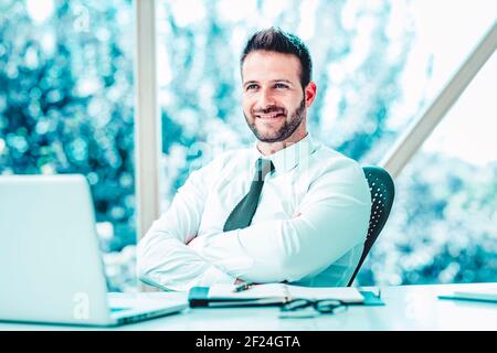 Aufnahme eines glücklichen Geschäftsmannes, der hinter seinem Laptop sitzt und arbeitet. Stockfoto