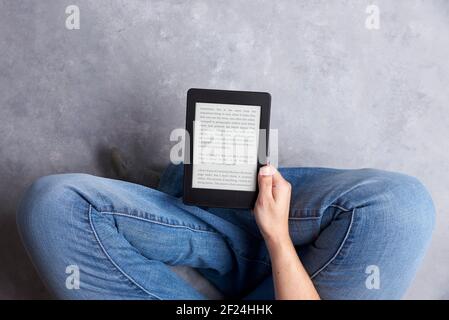 Subjektive Ansicht eines jungen Menschen, der einen Text auf einem elektronischen Leser liest. Konzepte: Technologie und Lesen. Bild mit Kopierbereich Stockfoto