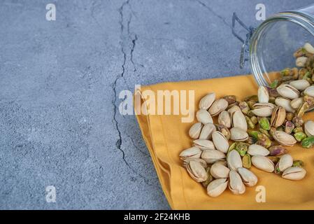 Viele natürliche Pistazien in Glasschale auf grauem Hintergrund geknackt Beton. Stockfoto