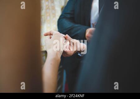 Ein flacher Fokus des Bräutigams, der einen Ring aufsetzt Der Finger der Braut während der Hochzeitsfeier Stockfoto