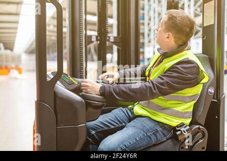 Lagermitarbeiter in Uniform arbeiten auf einem Sattelzug in einem modernen automatischen Lager. Lagerhaltung, Maschinenkonzept. Logistik auf Lager. Stockfoto