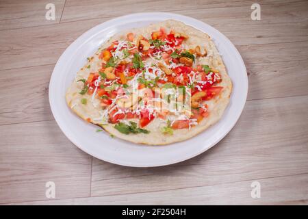 Uthappam oder Uttapam ist eine Art von Dosa aus Südindien, die dicker ist, mit Tomaten, Zwiebeln, Chili-Päckchen, Cashewnuss und Käse Stockfoto