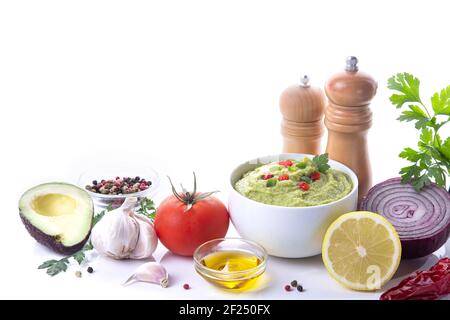 Schüssel mit Guacamole und Zutaten auf weißem Hintergrund mit Kopierraum. Stockfoto