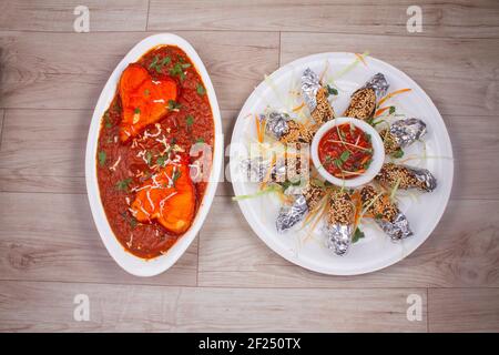 Paneer Butter Masala oder Fried Veg Rolle oder Abendessen Menü auf einem stimmungsvollen Hintergrund serviert, selektive Fokus Stockfoto