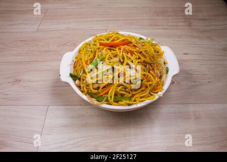 Eiernudeln mit gegrilltem Schweinefleisch auf chinesischen Tellern auf einem Holztisch und Dekoration Stockfoto