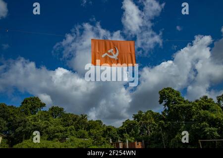 kommunistische Flagge. Hammer und Sichel, die die Bauern und die Arbeiter darstellen, fliegen im dichten, wolkigen blauen Himmel. Stockfoto