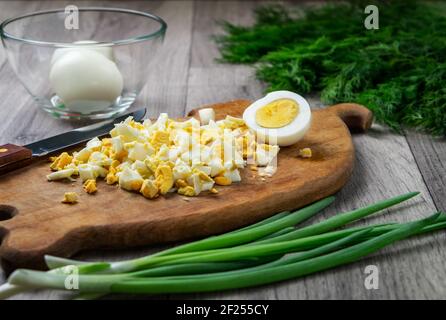 Gekochte Eier, fein gehackt auf alten Holzschneidebrett. Zutat für Salat. Home Food-Konzept. Natürliche Lebensmittel. Stockfoto