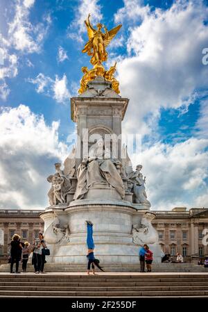 Touristen machen Fotos und Mädchen machen Handstand vor dem Queen Victoria Memorial, vor dem Buckigham Palace. London, Großbritannien. Stockfoto