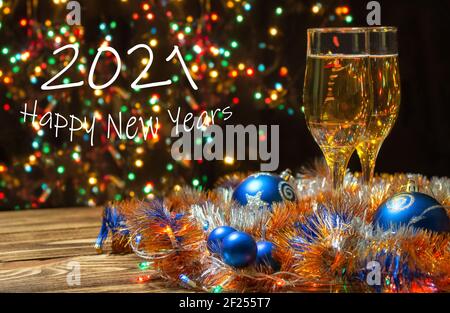Zwei Gläser Champagner, geschmückt mit blauen Weihnachtskugeln, einer Girlande, Neujahrsinsel auf rustikalem Hintergrund, mit Neujahrsbokeh. Neujahr und Stockfoto