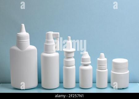 Ein vielfältiges Set aus weißen Kunststoffbehältern für Pharmazeutika, aufgereiht in der Reihenfolge der Größe in der Höhe. Auf hellblauem Hintergrund. Stockfoto