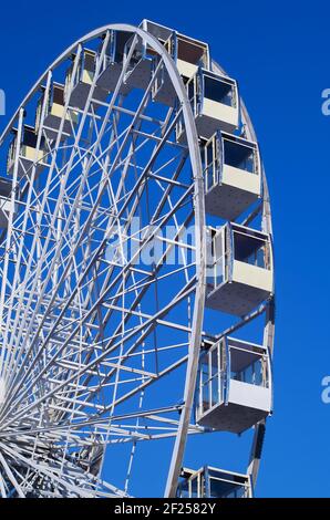 Modernes weißes Riesenrad mit geschlossenen Glaskabinen gegen den blauen Himmel. Nahaufnahme. Tourismuskonzept. Stockfoto