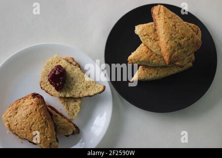 Hausgemachte, einfache, milde Buttermilch-Scones, vier davon auf einem grauen Teller gestapelt. Aufnahme auf weißem Hintergrund Stockfoto