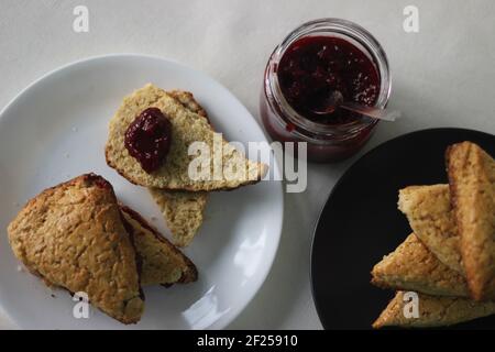 Hausgemachte, einfache, mild-süße Buttermilch-Scones, serviert zusammen mit hausgemachter Erdbeermarmelade. Aufnahme auf weißem Hintergrund Stockfoto