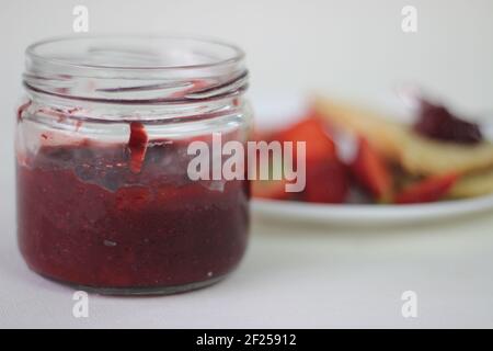 Halb-volle Flasche mit hausgemachter Erdbeermarmelade Schuss zusammen mit hausgemachten einfach milde Buttermilch Scones. Aufnahme auf weißem Hintergrund Stockfoto