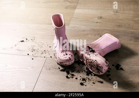 Schmutzige schlammige Kinder Gummi Regen Stiefel auf Laminatboden Stockfoto