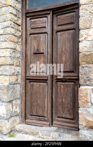 Architektonisches Detail einer massiven braunen Holztür in einem Massives braunes Steingebäude Stockfoto