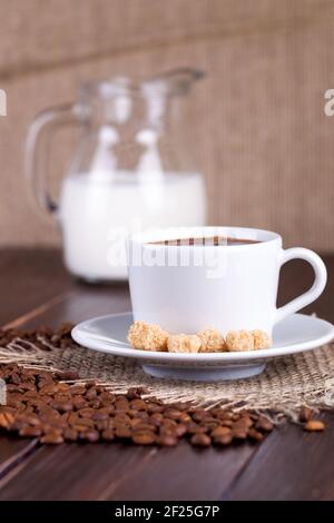 Kaffeetasse, Sahne, Kaffeesorten und Rohrzucker auf einem Tisch Stockfoto