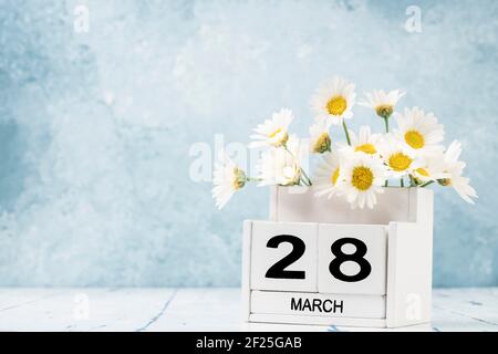 White Cube Kalender für märz mit Gänseblümchen über geschmückt Blauer Hintergrund mit Kopierbereich Stockfoto