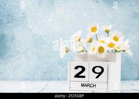 White Cube Kalender für märz mit Gänseblümchen über geschmückt Blauer Hintergrund mit Kopierbereich Stockfoto