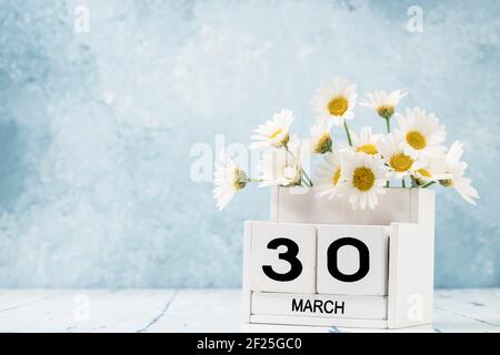 White Cube Kalender für märz mit Gänseblümchen über geschmückt Blauer Hintergrund mit Kopierbereich Stockfoto