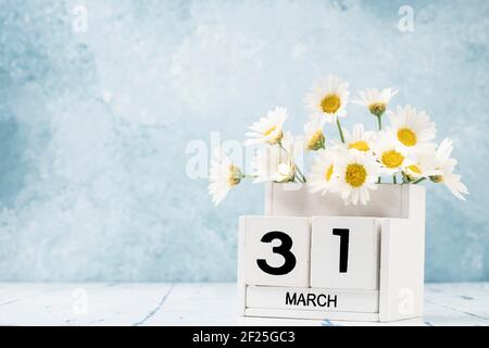 White Cube Kalender für märz mit Gänseblümchen über geschmückt Blauer Hintergrund mit Kopierbereich Stockfoto