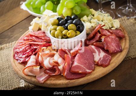 Antipasti Teller mit Speck, Trockenfleisch, Salami, Käse und Trauben auf einem hölzernen Hintergrund catering Stockfoto