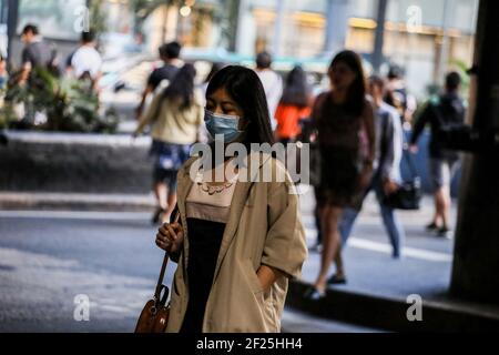 Eine Frau, die eine Schutzmaske trägt, um die Ausbreitung der Coronavirus-Krankheit zu verhindern, überquert eine Straße während einer gemeinschaftlichen Quarantäne in Manila, Philippinen. Stockfoto