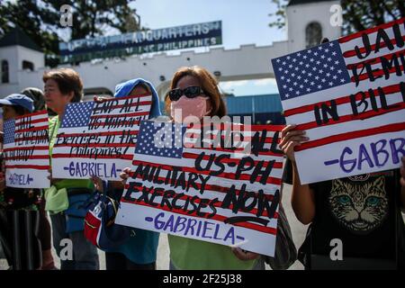 Aktivisten halten Plakate gegen die fortgesetzte Präsenz von US-Stützpunkten im Land vor einem Militärhauptquartier in Manila auf den Philippinen. Stockfoto