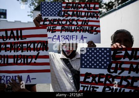 Aktivisten halten Plakate gegen die fortgesetzte Präsenz von US-Stützpunkten im Land vor einem Militärhauptquartier in Manila auf den Philippinen. Stockfoto