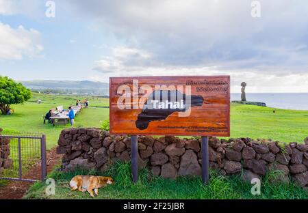 Namensschild am Tahai Zeremonialkomplex, Hanga Roa, Westküste der Osterinsel (Rapa Nui), Chile mit Ahu Ko Te Riku Moai Statue im Hintergrund Stockfoto