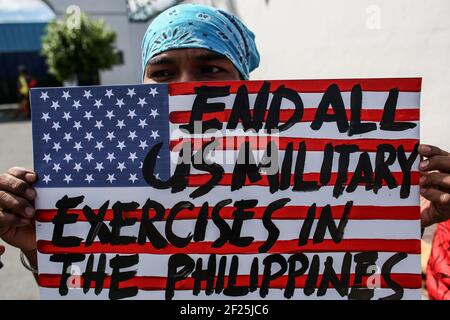 Aktivisten halten Plakate gegen die fortgesetzte Präsenz von US-Stützpunkten im Land vor einem Militärhauptquartier in Manila auf den Philippinen. Stockfoto