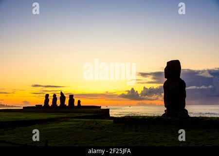 Moai (Tahai und Ahu Vai Ure) mit dem Rücken zur Pazifikküste bei Ahu Tahai, Hanga Roa, Westküste der Osterinsel (Rapa Nui) bei Sonnenuntergang Stockfoto