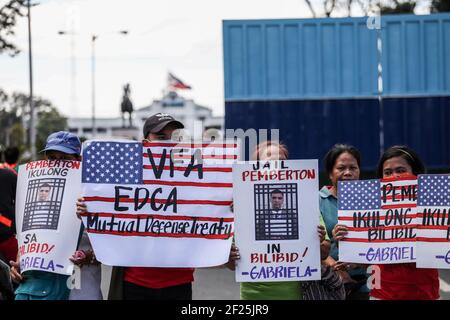 Aktivisten halten Plakate gegen die fortgesetzte Präsenz von US-Stützpunkten im Land vor einem Militärhauptquartier in Manila auf den Philippinen. Stockfoto