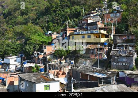 Typische Favela-Häuser am Hang und lokale Kirche im Viertel Santa Marta in Rio de Janeiro, Brasilien. Stockfoto