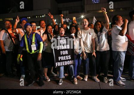 Unterstützer und Mitarbeiter von ABS-CBN, dem größten Rundfunknetzwerk des Landes, zünden Kerzen an und rufen Slogans an, während sie sich einem Protest vor dem ABS-CBN-Gebäude in Manila, Philippinen, anschließen. Stockfoto