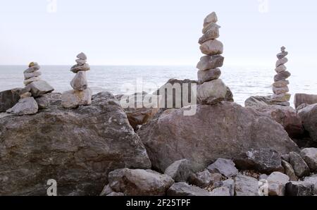 Kunst, Disziplin oder Hobby des Balancierens von Steinen oder Stapeln von Felsen zu Stein oder Stein cairns zu machen. Ausgewogen / gestapelt am Strand mit Meer dahinter. Stockfoto