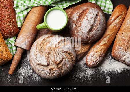 Verschiedene knuspriges Brot und Kelch von Milch auf blackboard Hintergrund. Ansicht von oben Stockfoto