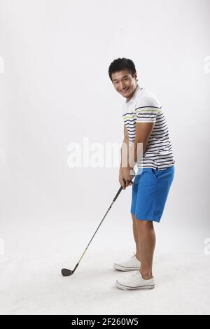 Ein junger Mann, der in legerer Kleidung Golf spielt Stockfoto
